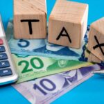 calculator and building blocks that spell TAX over Canadian five, ten and twenty dollar bills