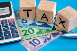 calculator and building blocks that spell TAX over Canadian five, ten and twenty dollar bills